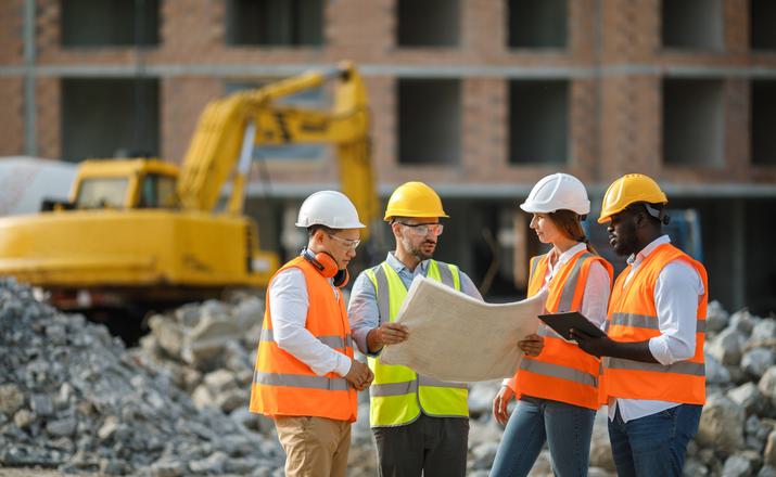 Construction workers on site looking at building plans Construction workers on site looking at building plans