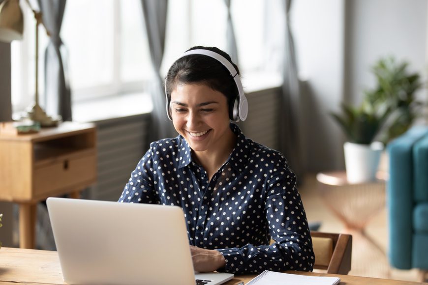 Woman wearing headphones on conference call on laptop Woman wearing headphones on conference call on laptop