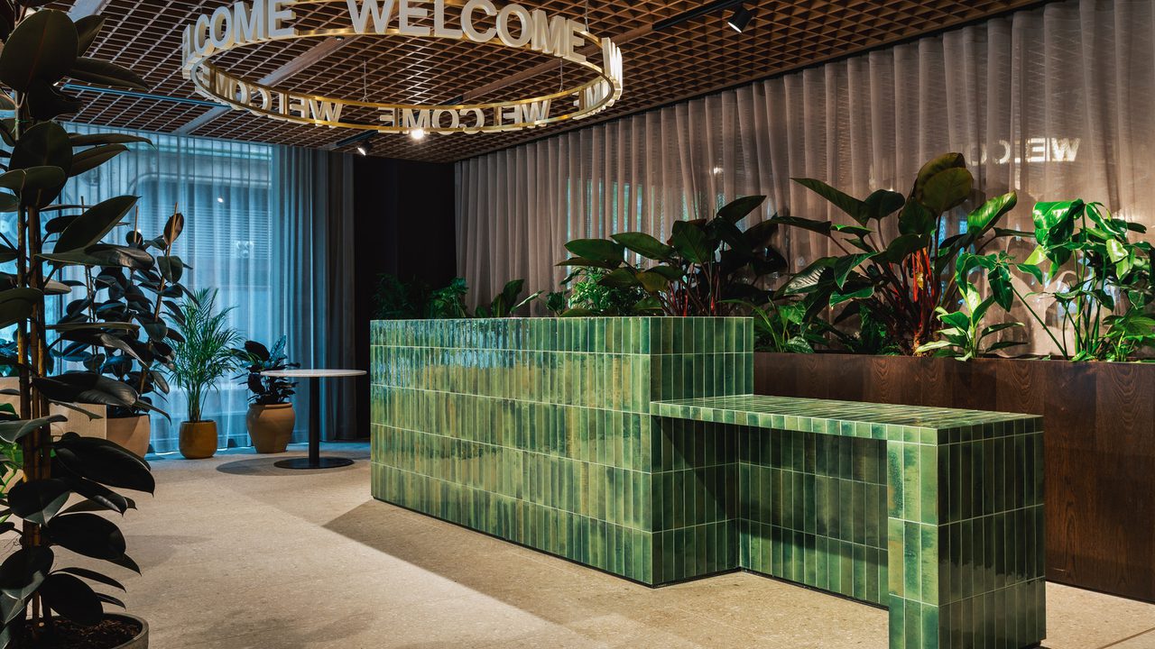 Reception area with green tiled reception desk and welcome sign hanging from ceiling Reception area with green tiled reception desk and welcome sign hanging from ceiling