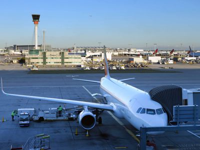 Airplane on the stand connected to the walkway at London's Heathrow airport. Control tower can be seen in the background. Airplane on the stand connected to the walkway at London's Heathrow airport. Control tower can be seen in the background.