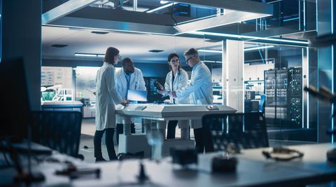 Team of people in white coats working on a bionic robot arm
