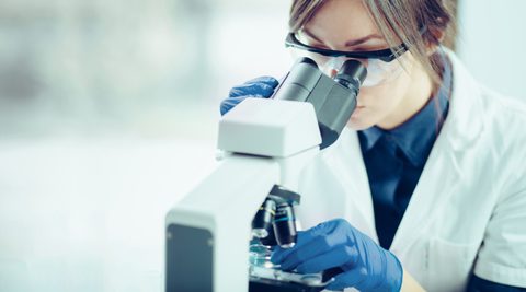 Female scientist looking through a microscope in a laboratory