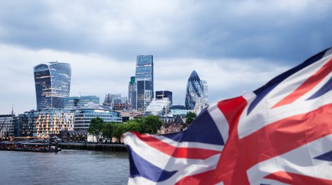 Towers in city of London with union jack flag in foreground